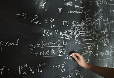 Mathematical formulas being written on a chalkboard